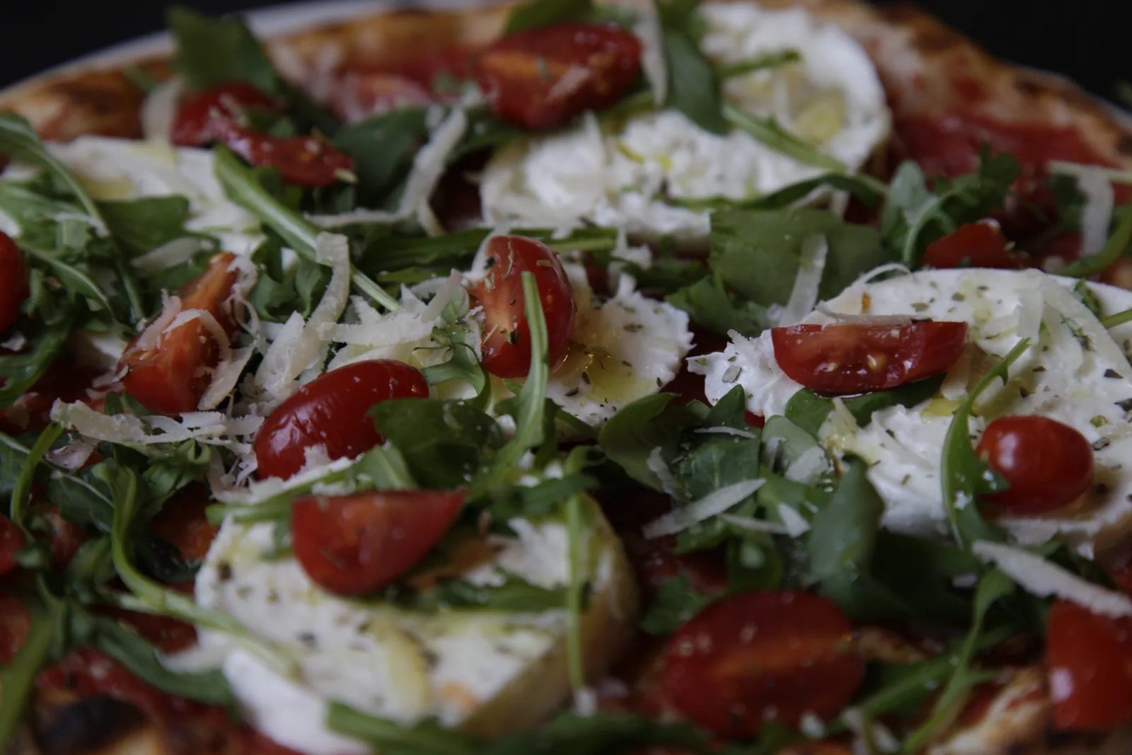 Una pizza con pomodorini, mozzarella e rucola