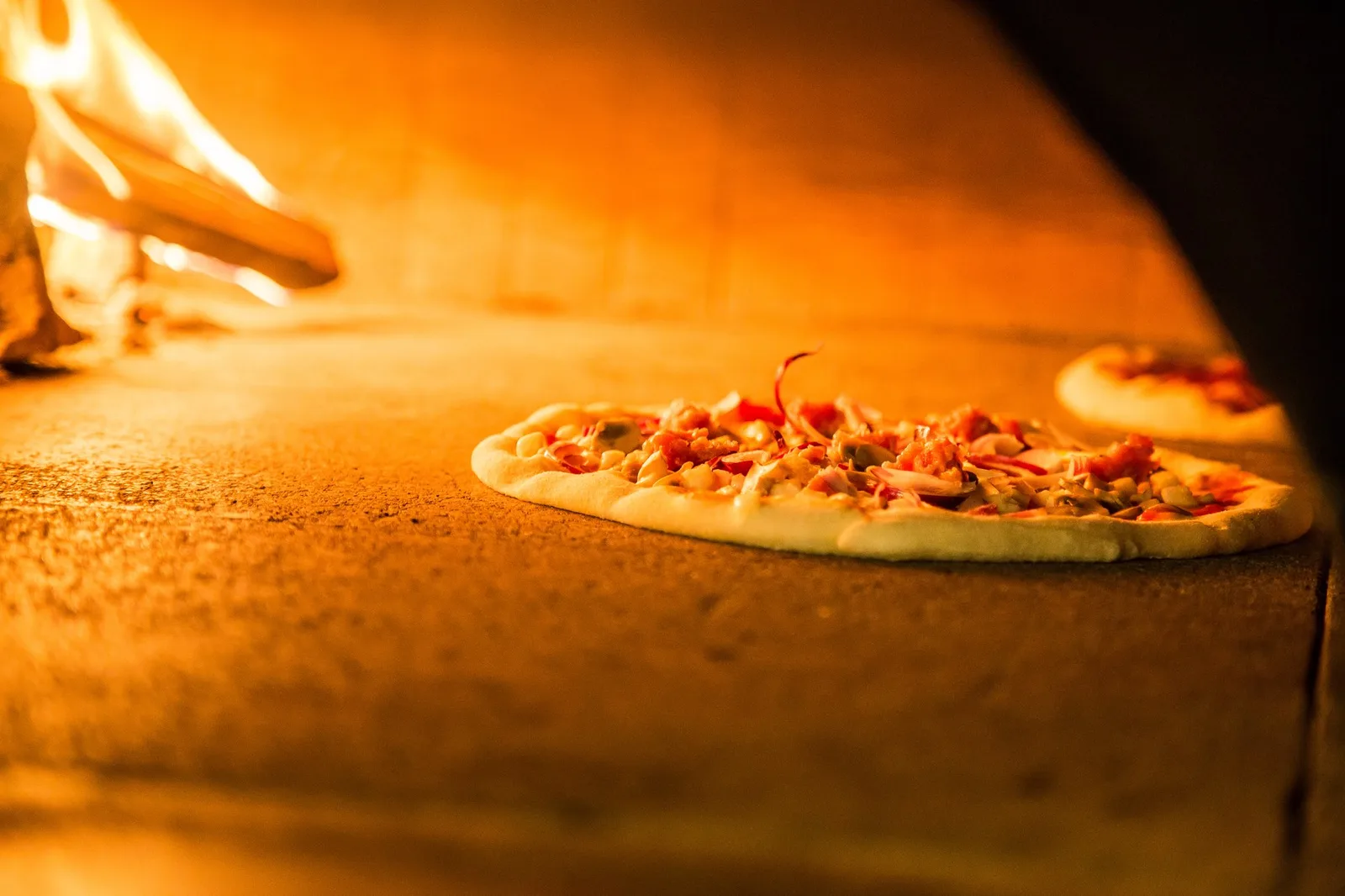Una pizza nel forno a legna, con la fiamma alta