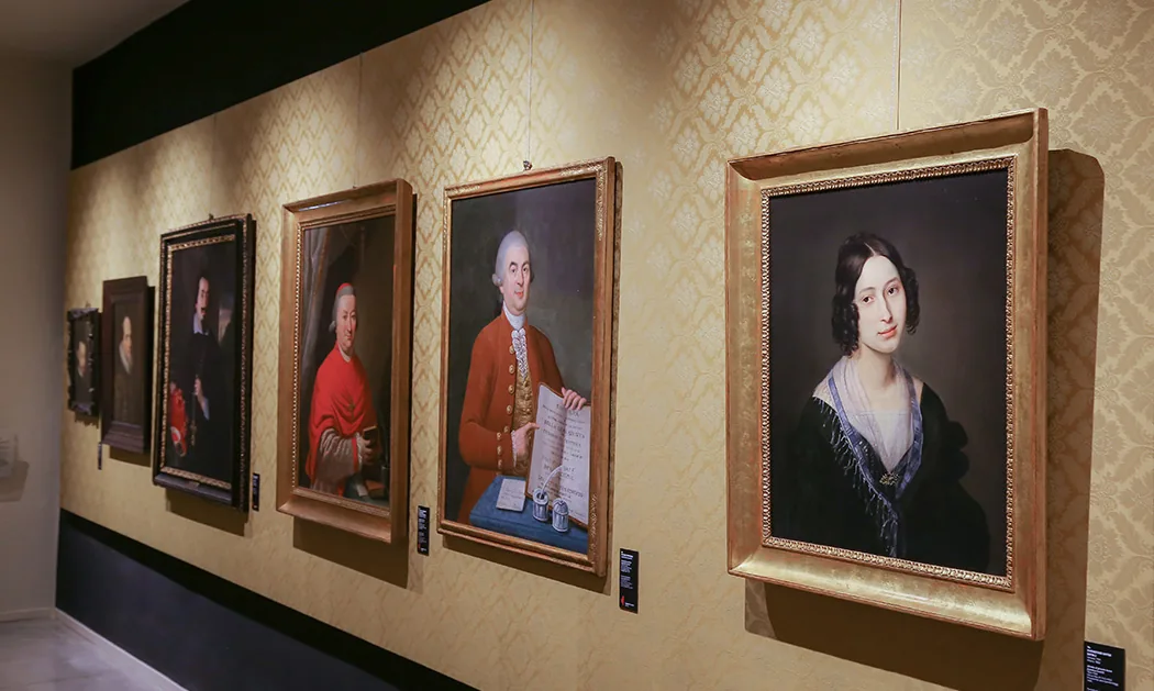 La galleria dei ritratti al primo piano, con i quadri allineati sulla parete a parati